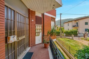 Un immeuble résidentiel avec une façade en briques, un portail en métal, un pot de fleurs et un petit balcon.