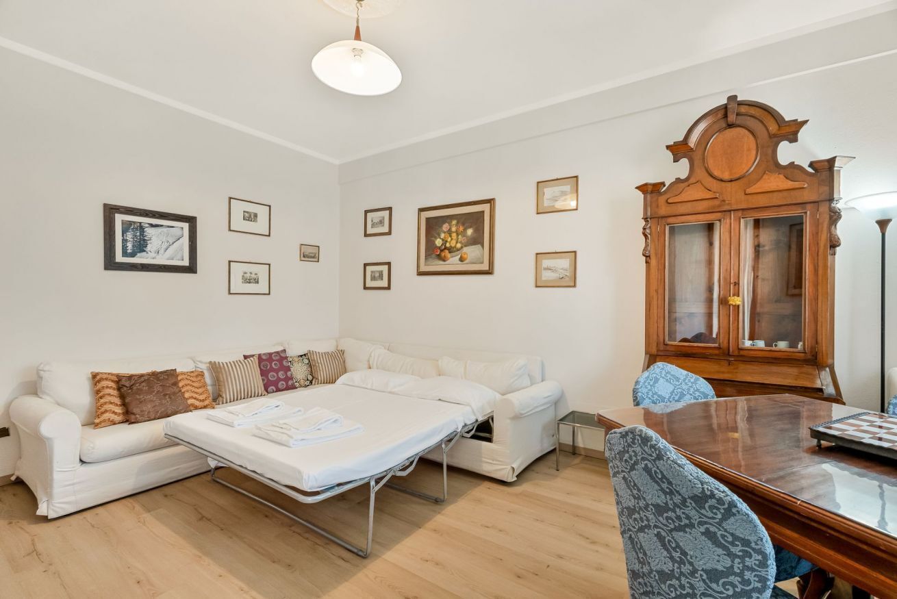 A room with a sofa, a dining table, and a cabinet.