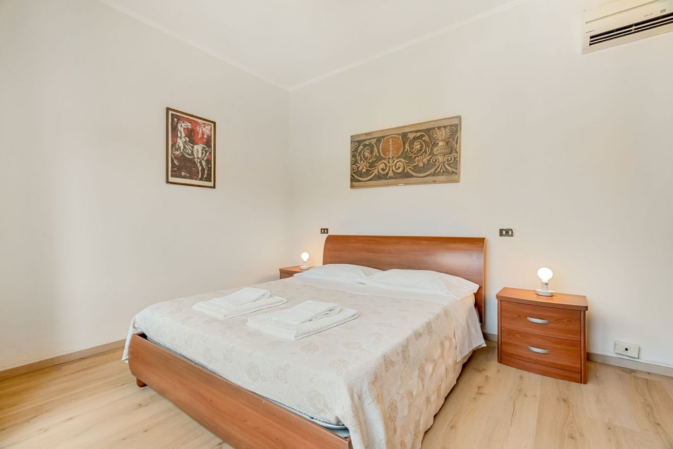 Une chambre à coucher avec un lit en bois, deux tables de chevet avec des lampes et des œuvres d’art accrochées aux murs.