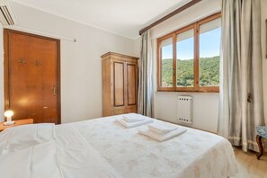 A hotel room with a bed, a wooden wardrobe, a radiator, and a window with a view of greenery. - [CasettaDellePunte]Road to lerici-Air conditioning (Romito Magra)