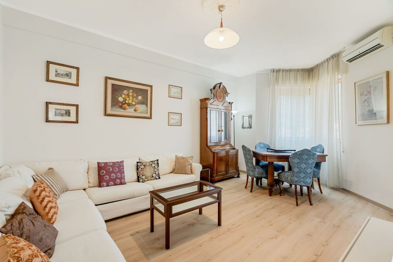 Ein Wohnzimmer mit Sofa, Couchtisch, Esstisch mit Stühlen und einer Standuhr.