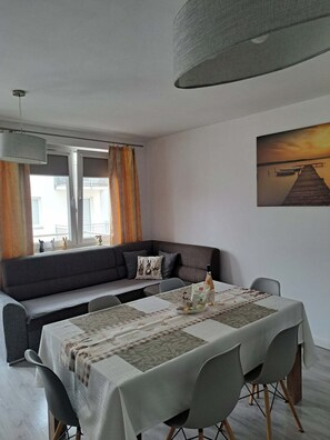 A modern living room with a sofa, dining table, and a painting on the wall. - THOMAS Vacation Rental (Świnoujście)