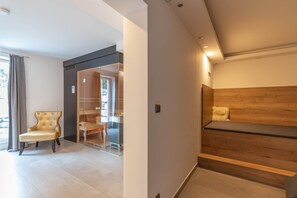 A modern interior with a wooden bench, a glass door leading to a balcony, and a tufted chair.