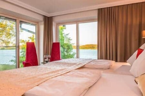 A hotel room with a bed, a desk, and a view of a lake.
