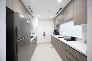 A modern kitchen with stainless steel appliances, a built-in oven, and a large window above the sink. - Bloomfields 1BR in Vantage 2- YGC (Abu Dhabi)