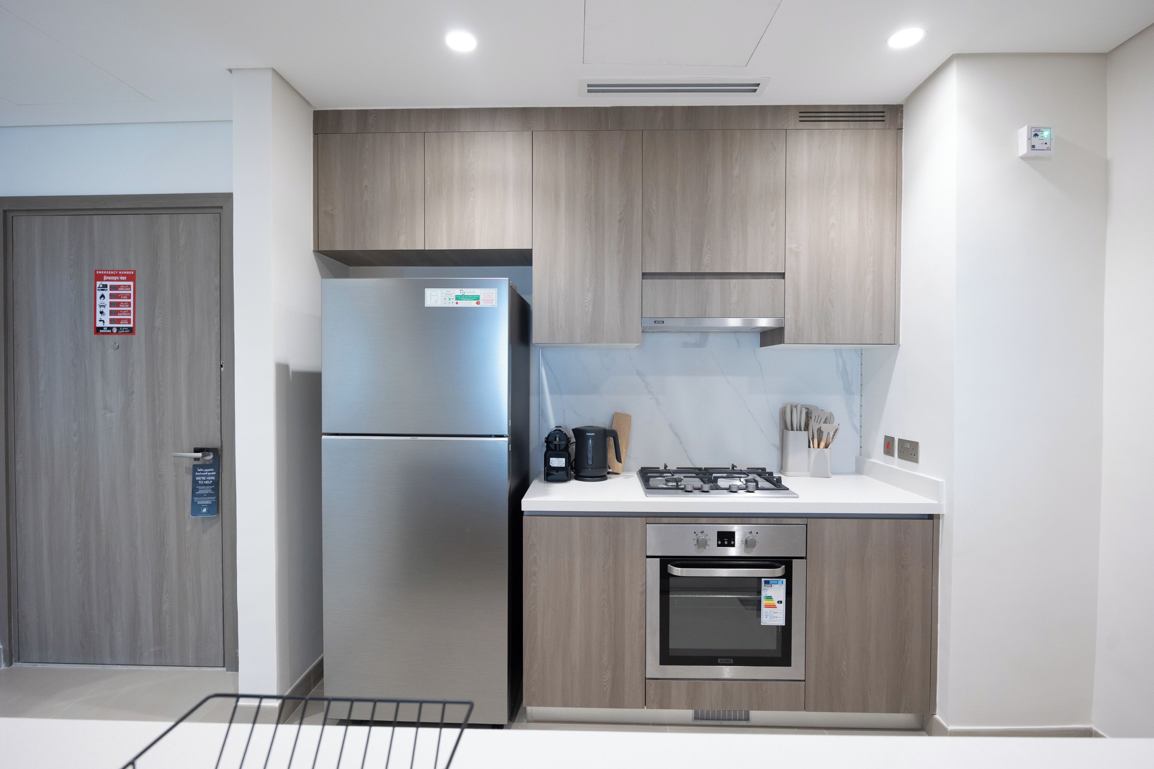 Une cuisine moderne dotée d’appareils électroménagers en acier inoxydable, de meubles en bois et d’un plan de travail blanc.