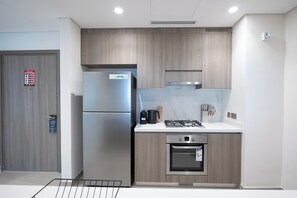 Une cuisine moderne dotée d’appareils électroménagers en acier inoxydable, de meubles en bois et d’un plan de travail blanc.