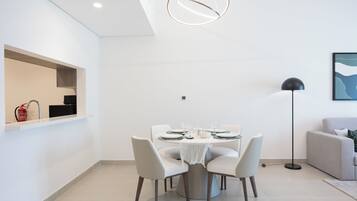 A modern dining area with a round table, white chairs, and a pendant light.