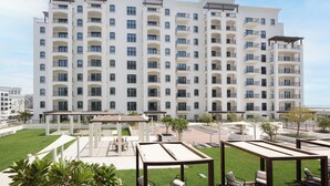 Un hotel de varios pisos con balcones, zonas de estar al aire libre y un césped bien cuidado.