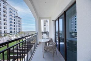 Un balcon avec une table et des chaises, une vue sur un immeuble et un ciel dégagé.