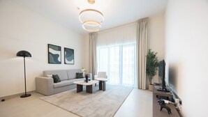 Una sala de estar moderna con sofá, mesa de centro, lámpara de pie y una obra de arte en la pared.
