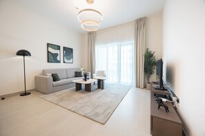 A modern living room with a sofa, coffee table, floor lamp, and artwork on the wall. - Bloomfields 1BR in Vantage 2- YGC (Abu Dhabi)