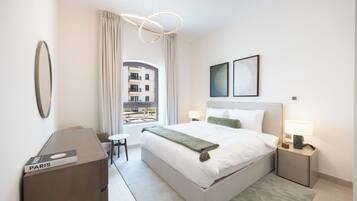 A modern hotel room with a large bed, bedside tables, a desk, and a view of the outside.