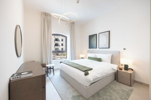 Une chambre d’hôtel moderne avec un grand lit, des tables de chevet, un bureau et une vue sur l’extérieur.