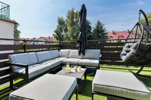 Ein Außenbereich mit Sitzgelegenheiten, darunter eine Couch, zwei Beistelltische und ein Hängesessel.