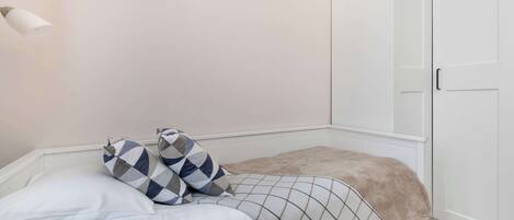 A bedroom with a bed, a bedside table, a wardrobe, and a wall-mounted light fixture.