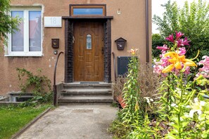 A house with a wooden front door, a number '18' sign, and a mailbox. - Spacious Apartment with a Large Balcony | 3 Bedrooms (Gdańsk)