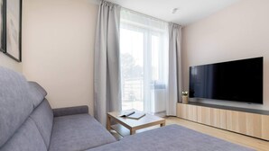 Ett modernt vardagsrum med en grå soffa, en platt-TV och ett litet bord med en bok på.