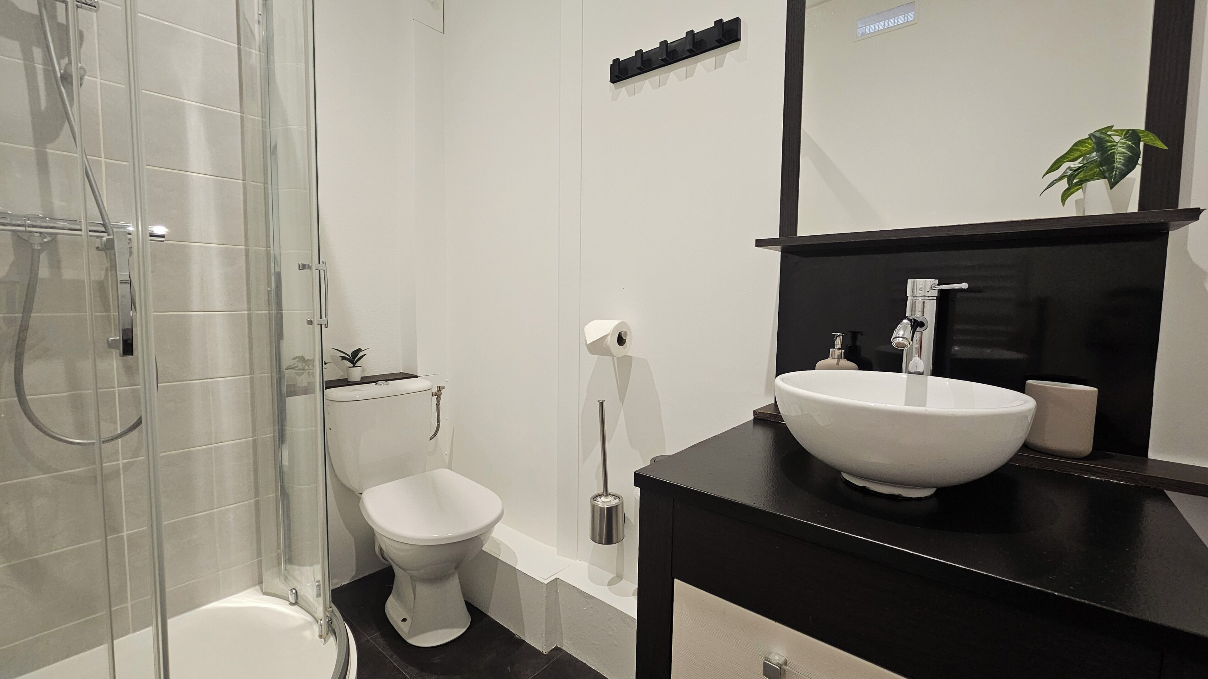 Une salle de bain moderne avec une douche à parois de verre, des toilettes et un meuble-lavabo doté d’un grand évier et d’un miroir.