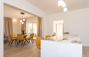 A modern dining area with a white table, yellow chairs, and pendant lighting. - Beautiful home in Biograd na Moru (Biograd na Moru)