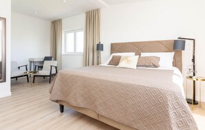 Ein Hotelzimmer mit einem großen Bett, einem Schreibtisch, einem Stuhl und einer Lampe.