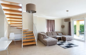 A modern living room with a wooden staircase, a sofa set, a dining table, and a view of the outdoors. - Stunning home in Porec (Porec)