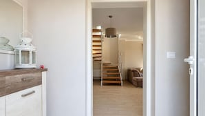Ein Flur, der zu einer Treppe mit Holzausstattung und einer hängenden Pendelleuchte führt.