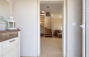 Ein Flur, der zu einer Treppe mit Holzausstattung und einer hängenden Pendelleuchte führt.