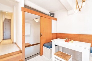 Eine kleine Küche mit weißer Arbeitsplatte, einem Holzschrank und einer Sitzecke.