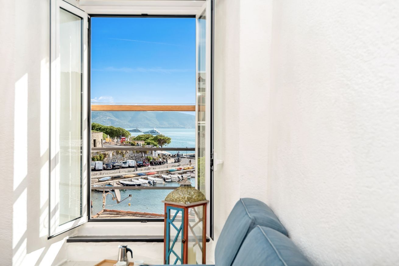 Un balcone con vista su un porto turistico, barche e una montagna in lontananza.