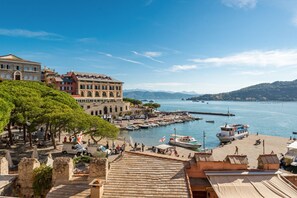 Eine Küstenstadt mit historischen Gebäuden, einem Hafen und Blick auf Meer und Berge.