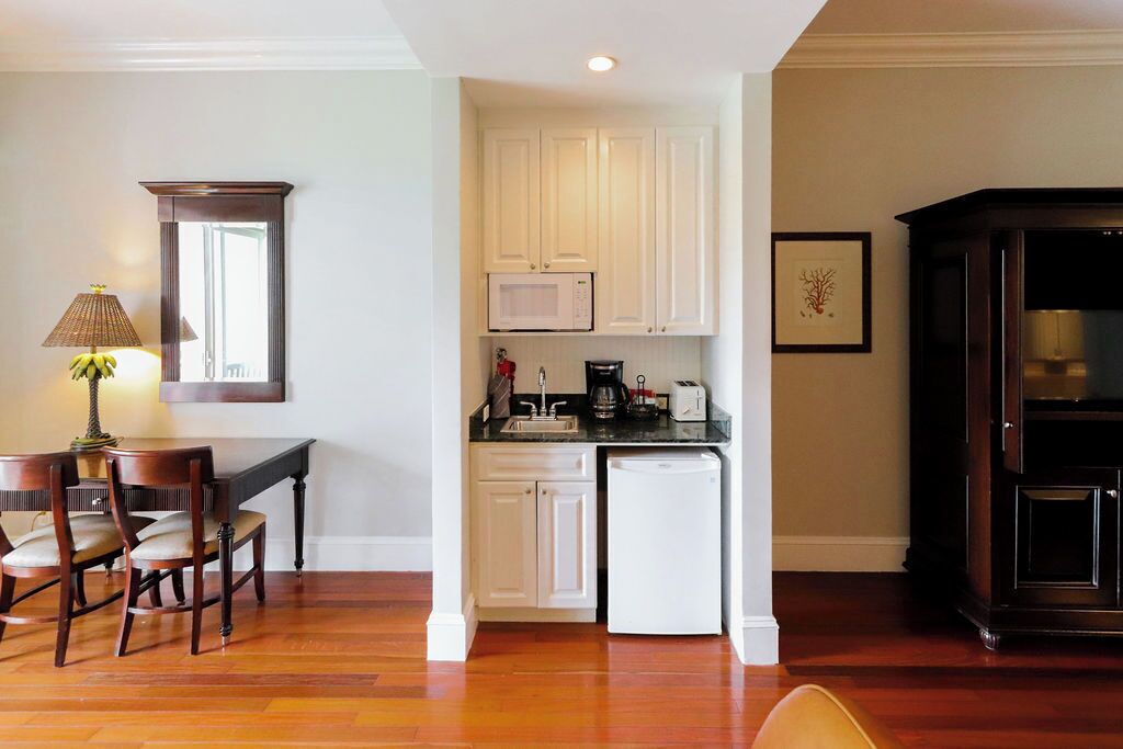A compact kitchen with white cabinets, a microwave, a sink, and a coffee maker.