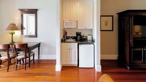 A compact kitchen with white cabinets, a microwave, a sink, and a coffee maker.
