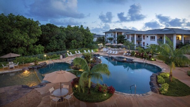 Un resort con una piscina grande, sillones de descanso y un jardín bien cuidado.