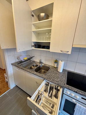Een keuken met witte kasten, een granieten aanrecht, een dubbele spoelbak en een oven.