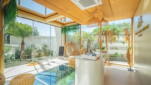 Um interior moderno com piscina de vidro, plantas de interior e um computador sobre uma escrivaninha.