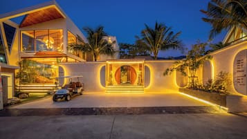 A modern house with a large glass facade, a golf cart, and a well-lit entrance.