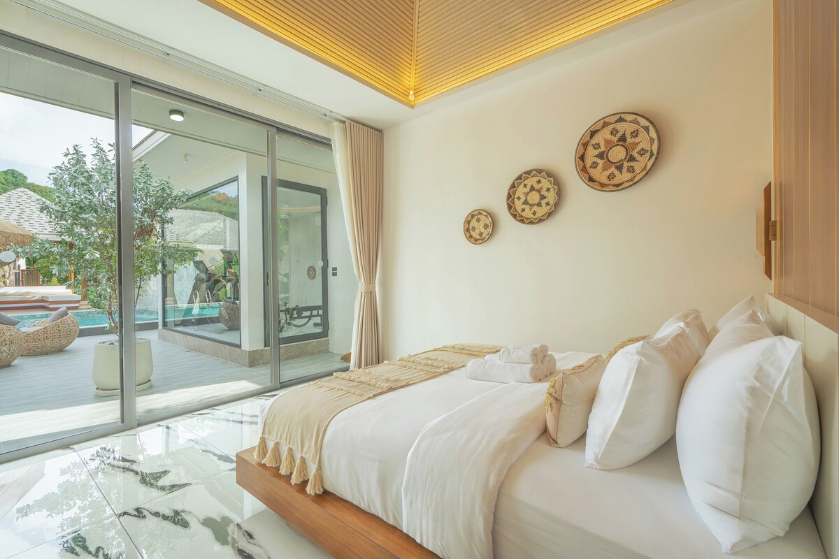 Quarto moderno com uma cama grande, vista para a piscina e duas placas decorativas na parede.