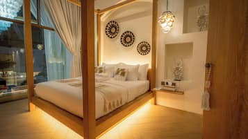 Quarto com cama de dossel, vigas de madeira, uma grande janela com cortinas e decoração nas paredes.