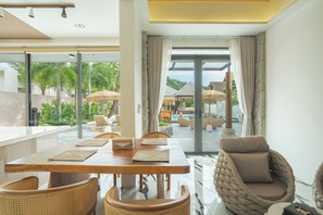 A modern dining area with a wooden table, woven chairs, and a view of a pool and outdoor seating. - Westkey Luxury Villa (Kathu)