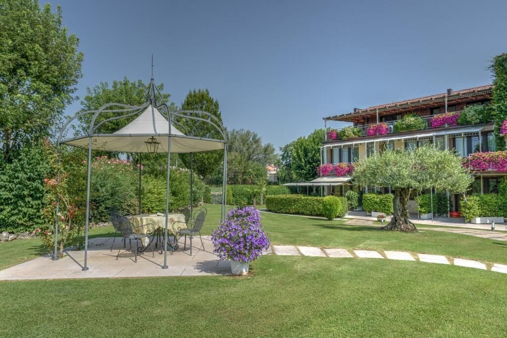 Ein Garten mit einem Pavillon, Sitzgelegenheiten im Freien und einem Gebäude mit Balkonen.
