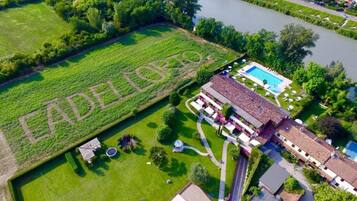 Vista aerea di una proprietà con piscina, campo da tennis e un ampio prato verde con la scritta 'EADELERTO'.