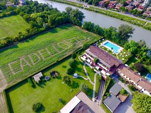 Ovenudblik over en ejendom med swimmingpool, tennisbane og en stor grøn mark med ordet 'EADELERTO' skrevet på den.