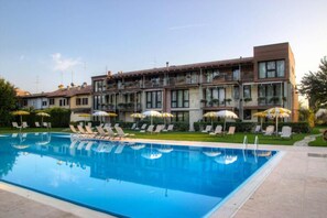 Et hotel med swimmingpool, liggestole og parasoller.