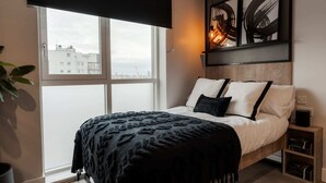 Una camera da letto con un letto, una finestra, vista sulla città e opere d'arte alle pareti.
