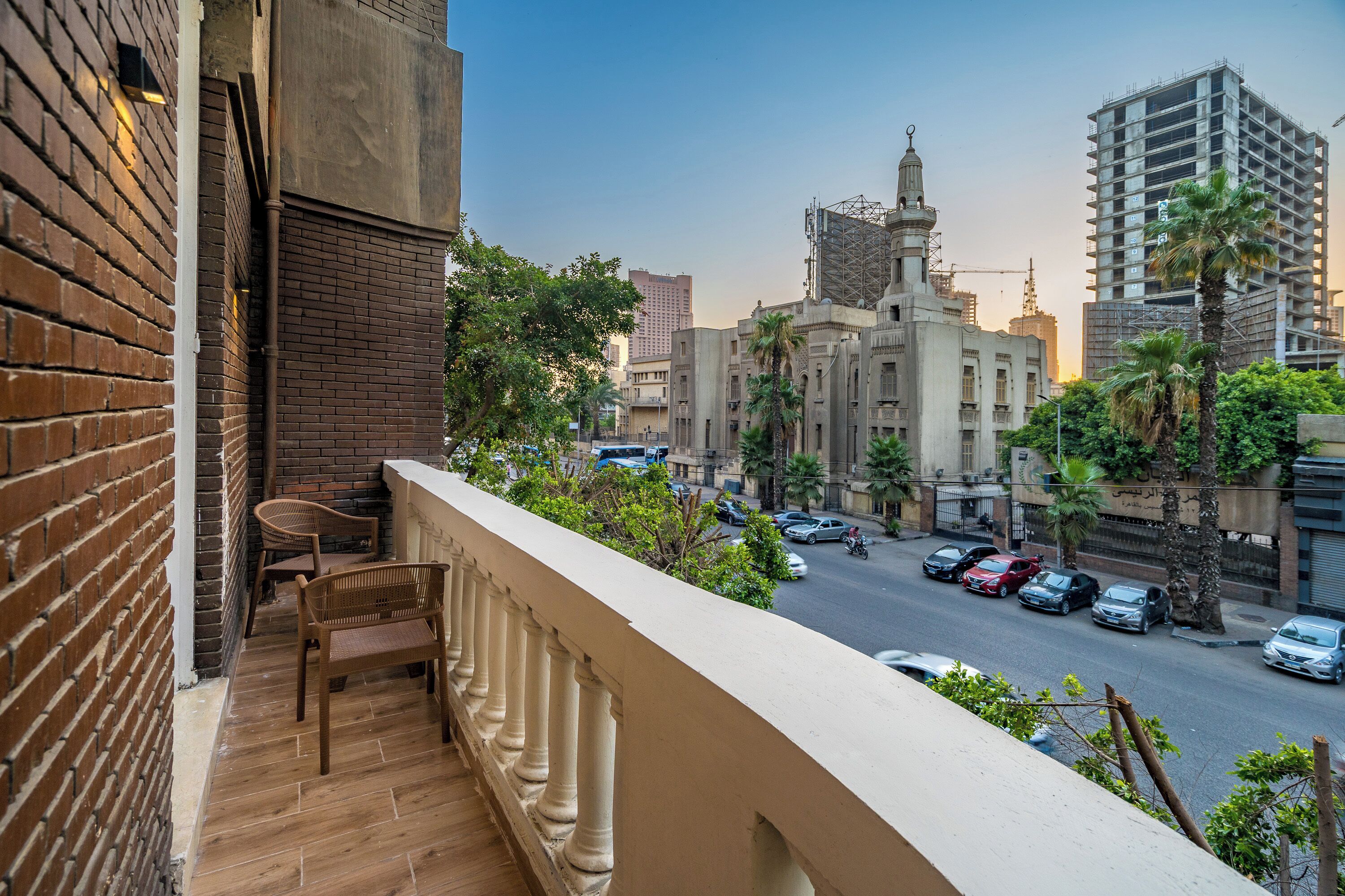 A balcony with a view of a cityscape, including a building with a dome and construction cranes.