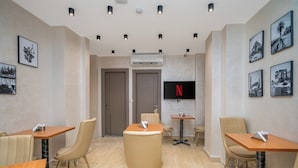 Quarto de hotel com área de jantar, televisão e obras de arte nas paredes.