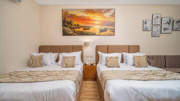 Ein Hotelzimmer mit zwei Betten, einem Sonnenuntergangsgemälde und mehreren gerahmten Bildern an der Wand.