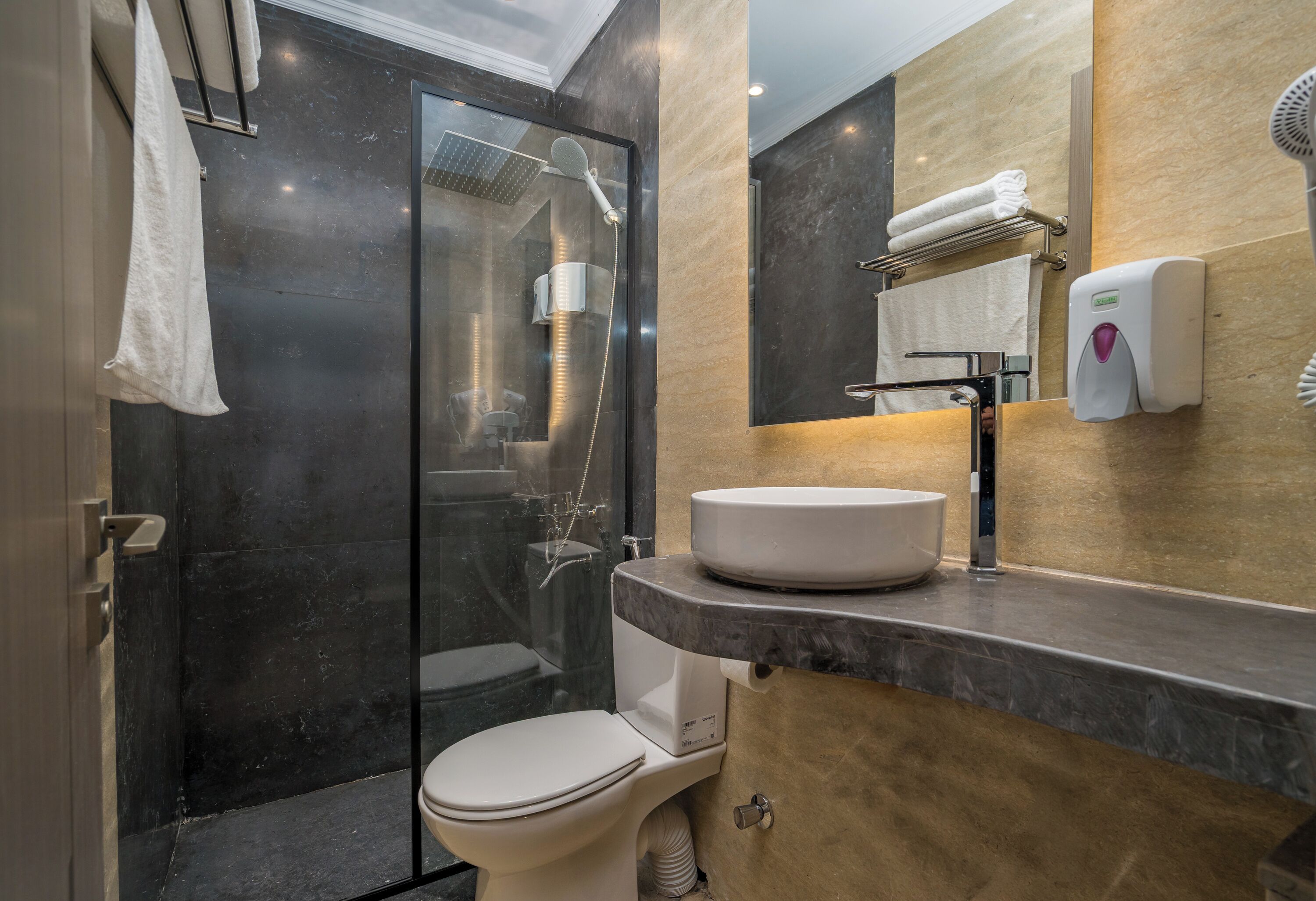 Une salle de bain moderne avec une douche à parois de verre, des toilettes blanches et un plan de toilette en marbre avec un lavabo.