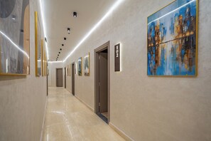 Pasillo de hotel con obras de arte en las paredes, un cartel con número y una puerta.